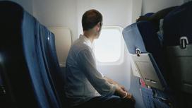 Пассажир сидит возле окна в самолете