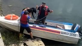 Двое мужчин усаживают собаку в лодку