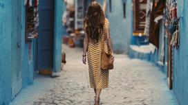 Девушка идет по улице синего города в Марокко