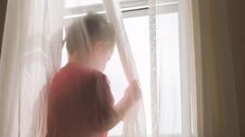 Ребенок стоит возле окна