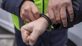 Полицейский одевает наручники на задержанного
