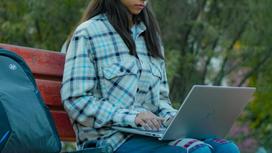Девушка сидит на лавочке с ноутбуком