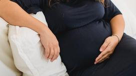 Беременная женщина сидит на диване