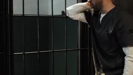 Заключенный стоит за решеткой в камере