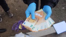 Полицейский держит в руках украденные деньги