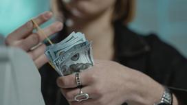 Девушка держит доллары в руке