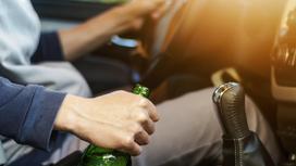 Мужчина на водительском сидении авто с бутылкой пива в руке