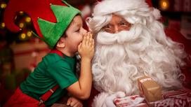 Ребенок в костюме эльфа шепчет на ухо Санта Клаусу