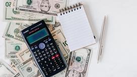Калькулятор, блокнот и ручка на долларовых купюрах
