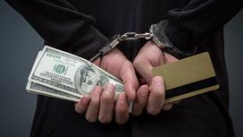 Человек в наручниках с деньгами и картой