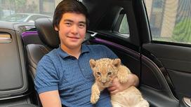 Алихан Байзаков держит львенка на руках