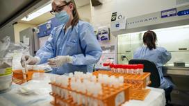 Девушки в голубых халатах работают в лаборатории