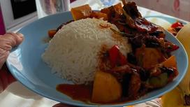 На тарелке уйгурское блюдо дапанджи и гарнир из длиннозерного риса