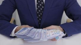Мужчина в строгом костюме и галстуке держит в руках большую сумму денег