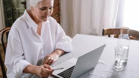 Женщина с седыми волосами сидит за компьютером