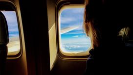Девушка смотрит в окно самолета