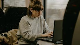 Девушка в очках смотрит в ноутбук