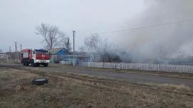 Пожарная машина стоит возле горящего дома