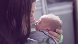 Женщина целует младенца