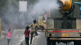 Дети бегут за грузовиком, разбрызгивающим воду на улицах