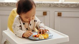 Ребенок ест руками из тарелки
