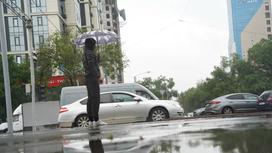 Человек с зонтом стоит у дороги