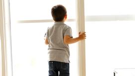 Мальчик стоит возле окна