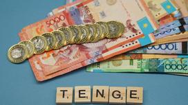 Деньги и кубики, выстренные в слово "TENGE".