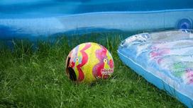 Мяч лежит на траве рядом с надувным матрасом