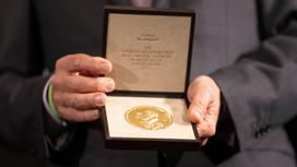 Нобелевская медаль по экономике в руках Гвидо Имбенса в 2021 году