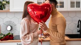 Парень и девушка держат в руках бокалы с шампанским и шар в виде сердца
