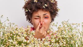 Женщина с насморком в окружении цветов
