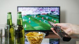 Человек смотрит футбол с пивом и чипсами