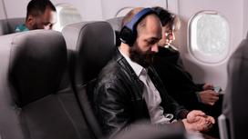 Мужчины сидят в кресле самолета с телефонами