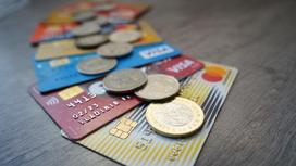 Банковские карты и монеты тенге лежат на столе