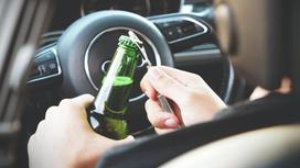 Водитель за рулем открывает бутылку пива