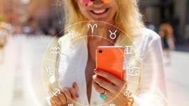 Девушка держит в руках смартфон на фоне изображения знаков зодиака