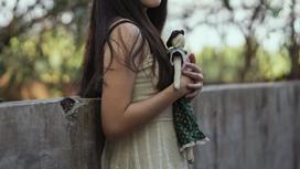 Девочка стоит на улице с куклой в руках