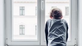 Мальчик стоит у окна