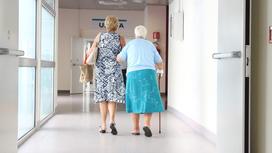 Бабушка и женщина идут по коридору больницы
