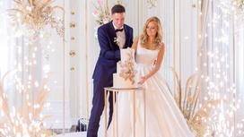 Жених и невеста разрезают трехъярусный свадебный торт