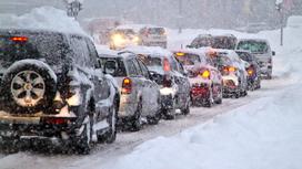 Машины едут по дороге во время снегопада
