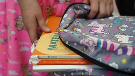 Девочка кладет книги в портфель
