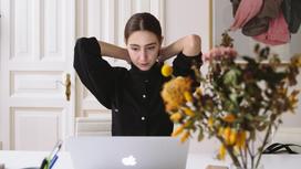 Женщина в черной блузке сидит за компьютером