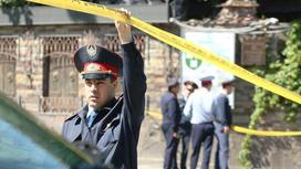 полицейский держит ленту рядом с местом преступления