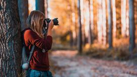Девушка с фотоаппаратом в парке осенью