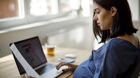 Беременная женщина работает за компьютером
