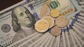Тенговые монеты лежат на долларовых банкнотах