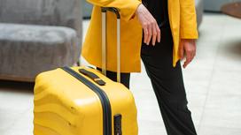 Девушка держит желтый чемодан