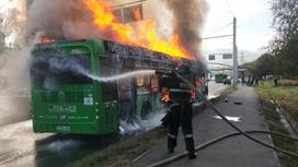 Пожарный тушит горящий автобус